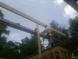 Carpenter setting a ridge beam over a new addition frame — Ice Dam Removal by Roofing Brothers in Ohio City