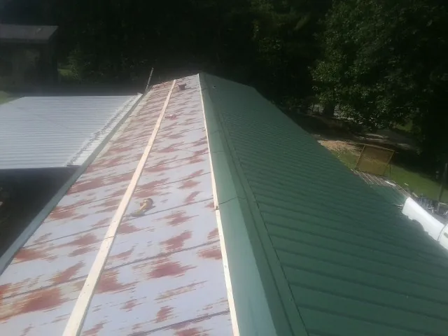 Old rusted panels beside newly installed green metal roofing — Wind Damage Roof Repair by Roofing Brothers in Ohio City