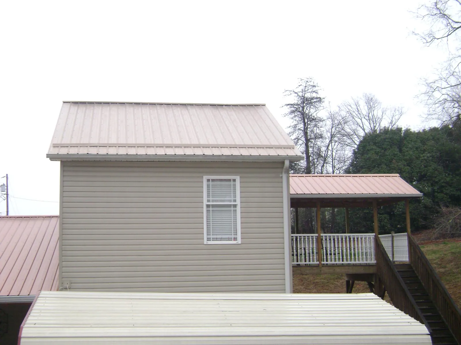Tan metal roofs on a two story addition and attached porch, from a Roof Replacement job in Ohio City