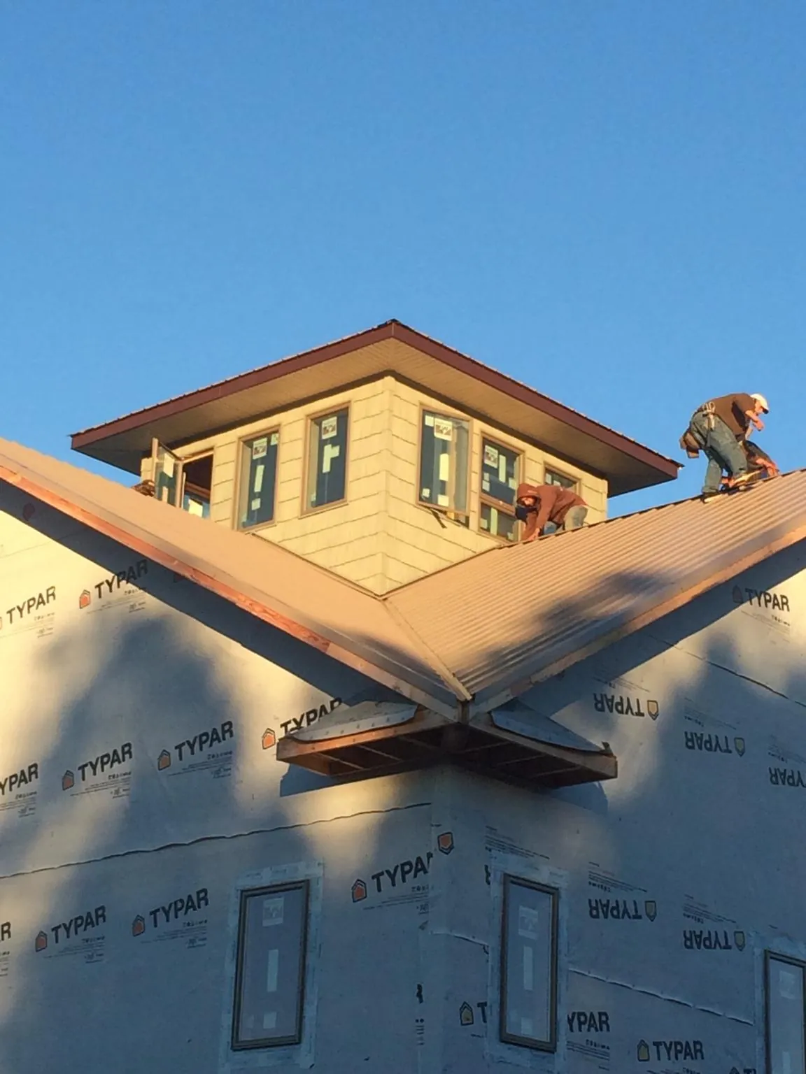 Roofers working around a rooftop cupola on a new metal roof at sunset — Roof Waterproofing in Ohio City by Roofing Brothers